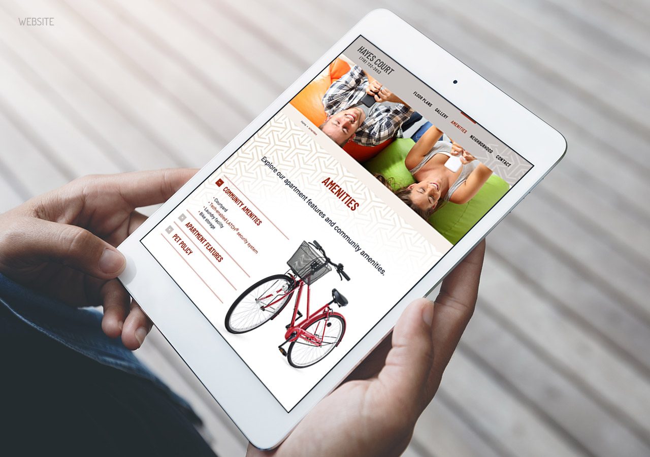 Person holding a tablet displaying a website featuring a red bicycle and promotional content with a vibrant orange and green banner.