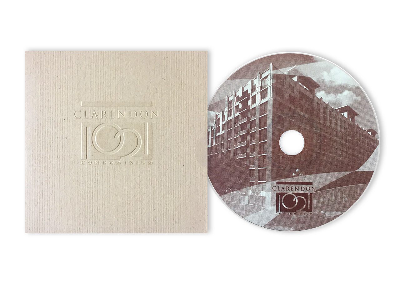 A CD with a cityscape design next to a beige textured sleeve featuring a minimalist camera icon.