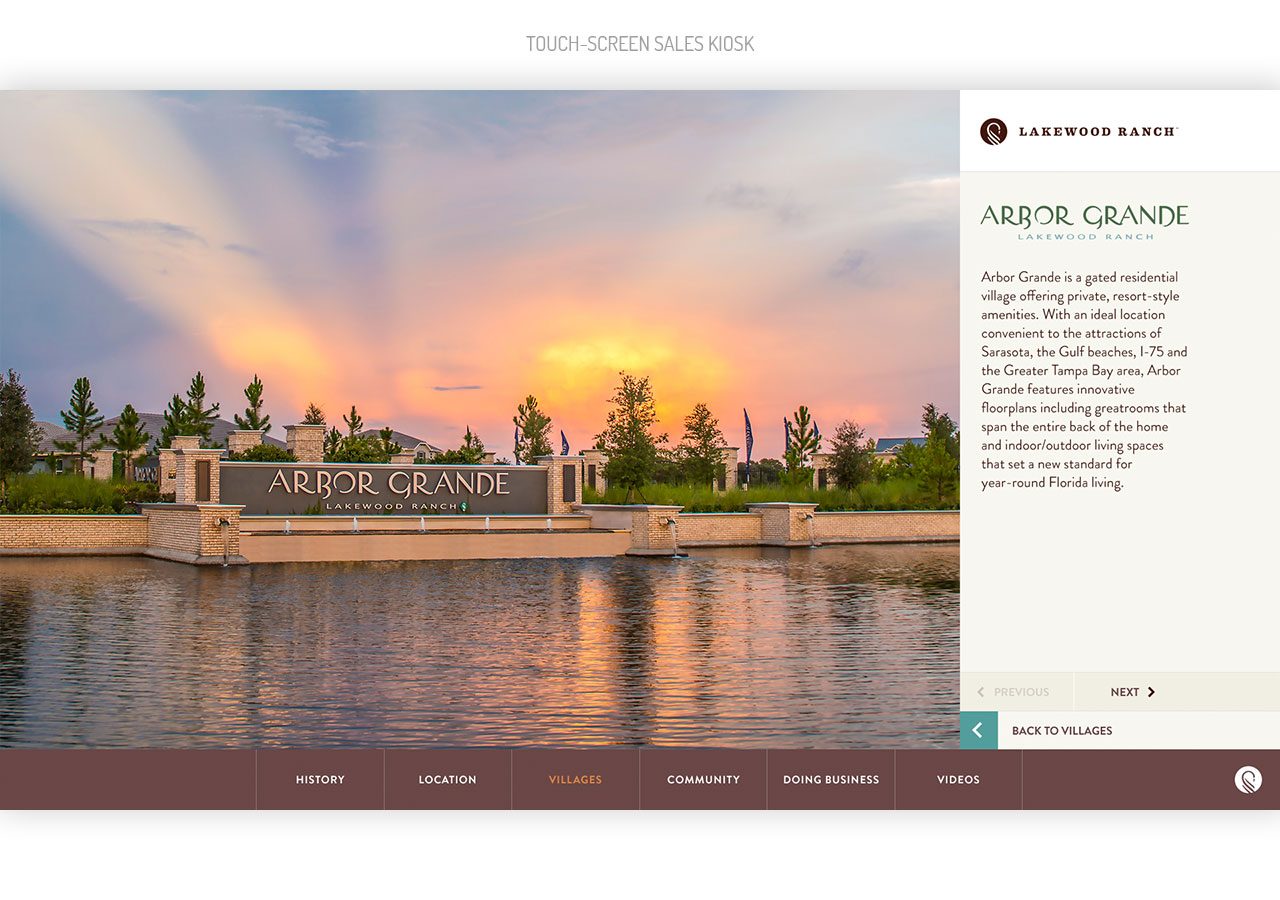 Sunset over a lakeside park with a stone sign reading "Aspen Grove" and calm water reflecting the colorful sky.